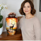 Woman holding a decorative urn with a deer design on a wooden surface.